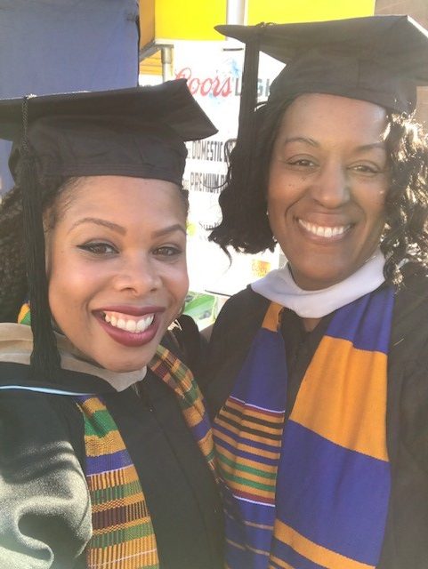Rashida Willard and Lora Whitfield at Commencement in caps and gowns, smiling