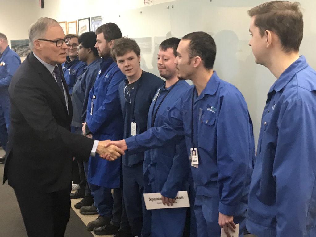 Gov. Inslee shake hands with a line of mechatronics students.