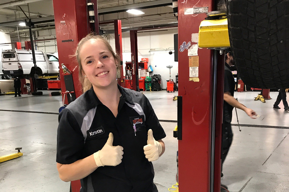 Kristin Kepner with thumbs up in a automotive shop
