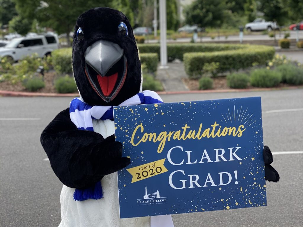 Oswald in a parking lot holding a sign that reads "Congratulations 2020 Clark Grad!"