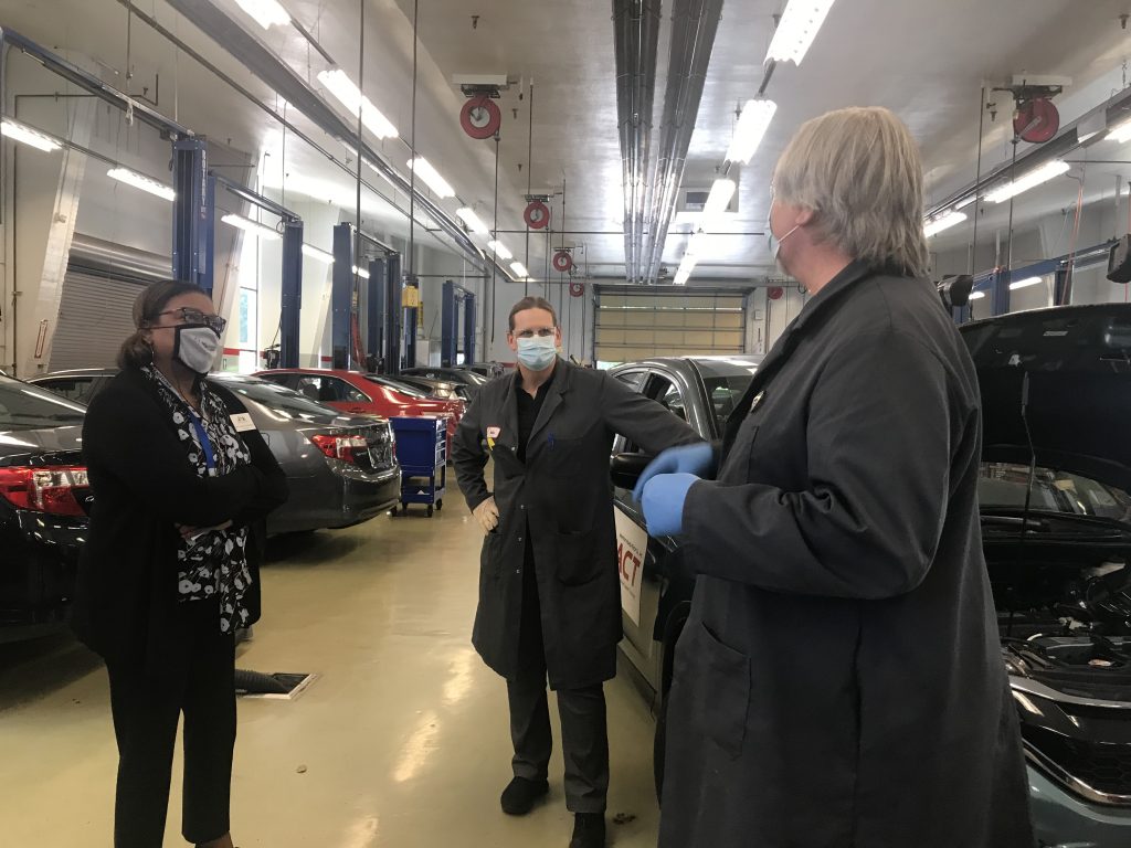 Dr. Karin Edwards and professors Tonia Haney and Mike Godson, all wearing PPE masks, in a car-filled garage.