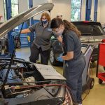 two students examine car engine
