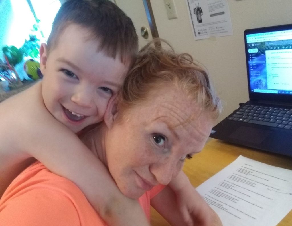Jessica Bull at her computer with her toddler son on her back