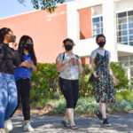 four students in face masks walking outside Cannell Library