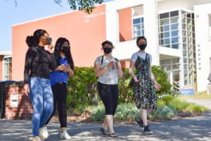 four students in face masks walking outside Cannell Library