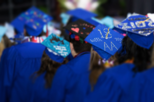 Graduates seen from behind, with decorated cap that reads "18 with my AA"
