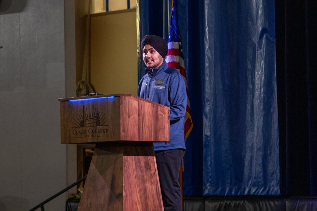 ASCC President Gurraj Singh Dhami stands at a podium.