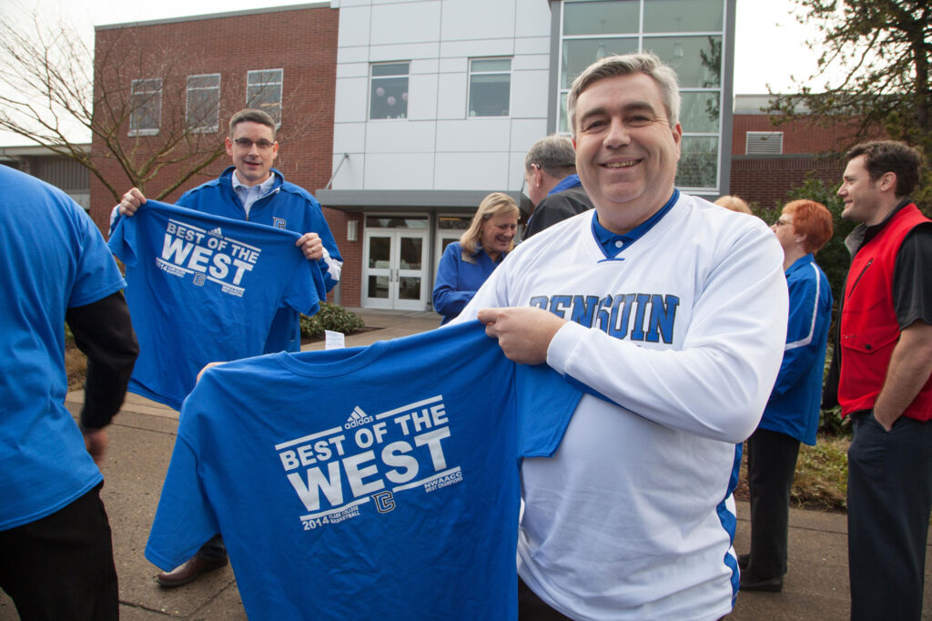 Former Clark College's President holding up a shirt that reads "Best of the West".