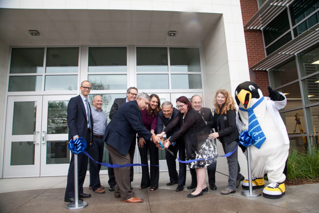 A group of people participating in a ribbon-cutting ceremony to mark the opening of a building.