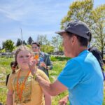 Steven Clark (Biology) shows future penguin Megan a pollinator her captured in the STEM bee garden. Megan's mother Rachel works in WES.