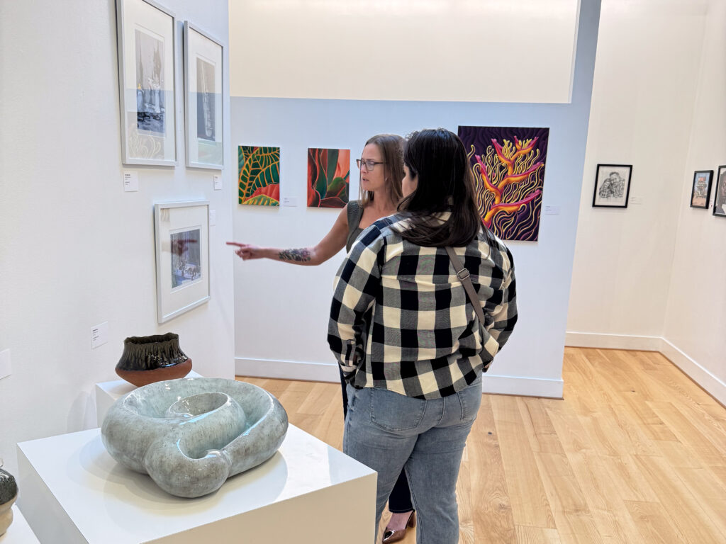 two people in front of artwork, one points