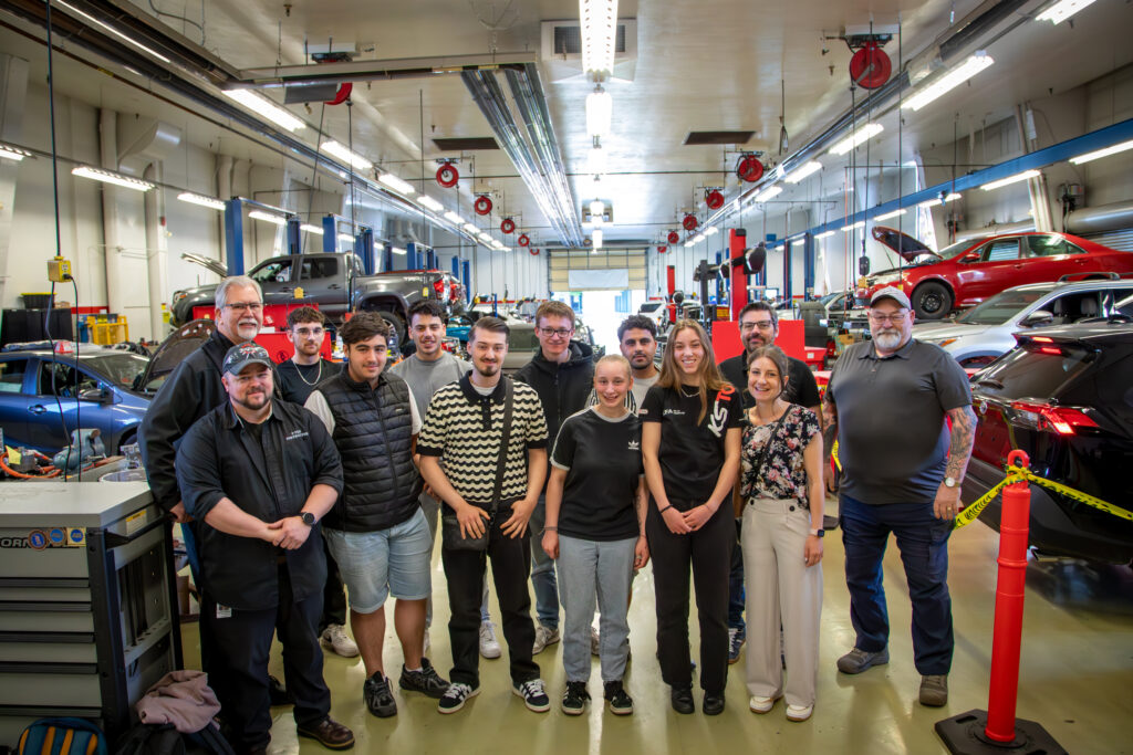 group photo of students and teachers in automotive lab.