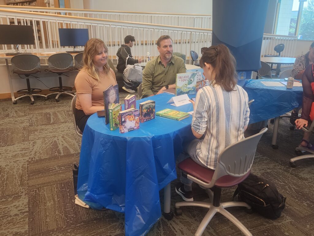 two people on one side of desk talking to another person