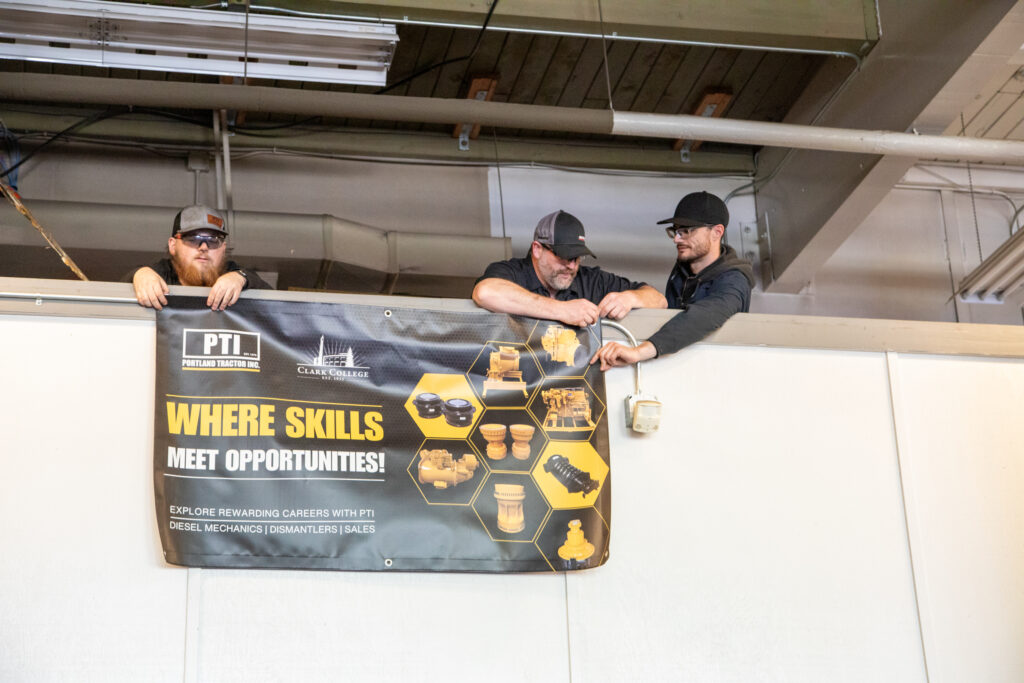 Three people secure a banner to wall from above.