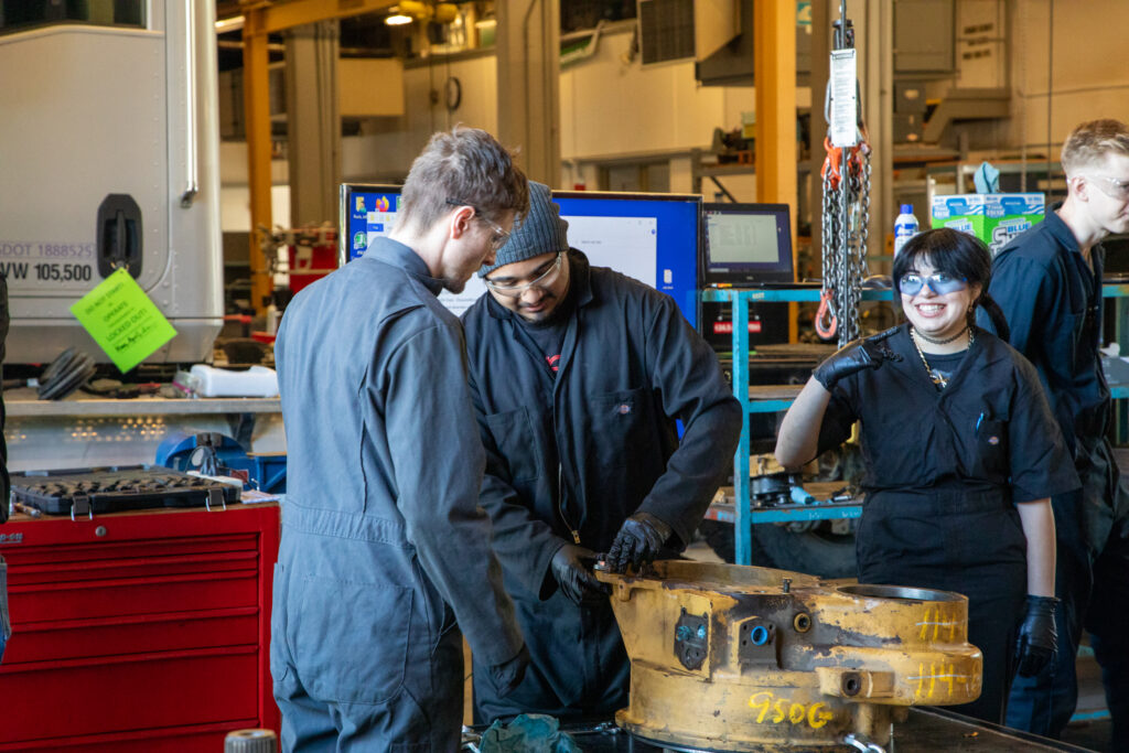3 students work on engine parts
