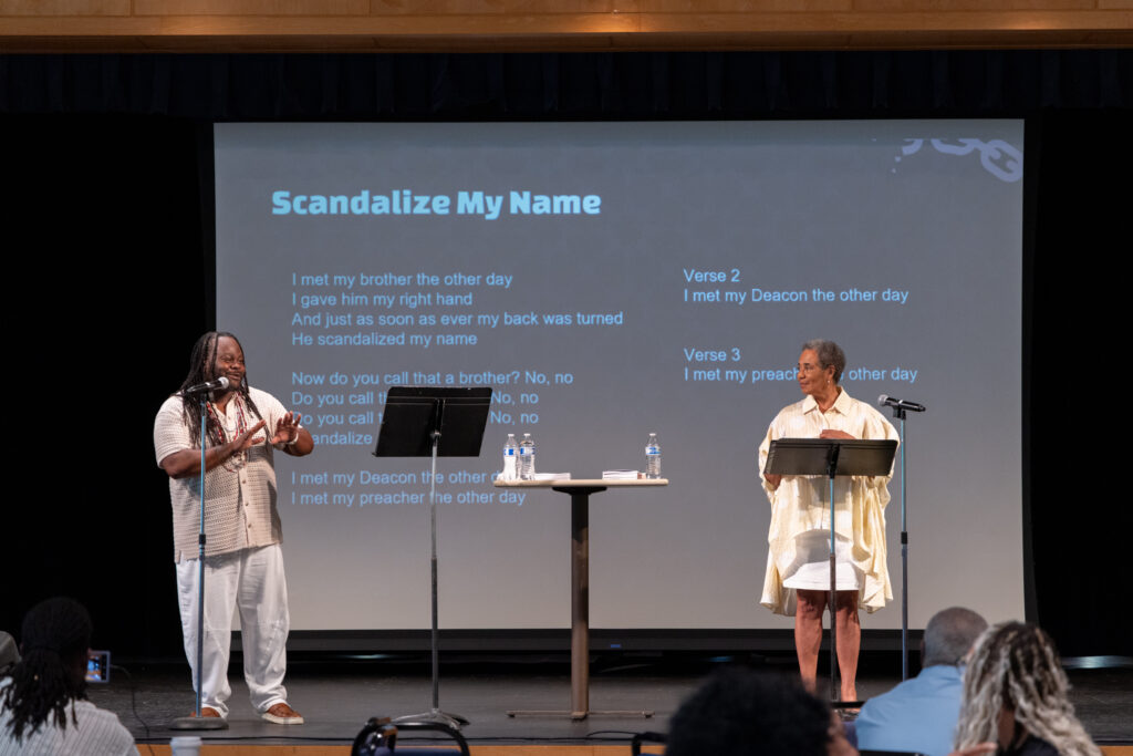 two people on stage with lyrics behind