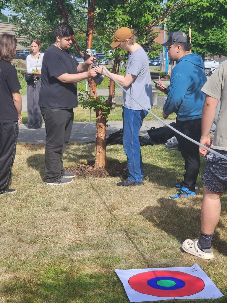 two people put a device on a string, while others stand around them.