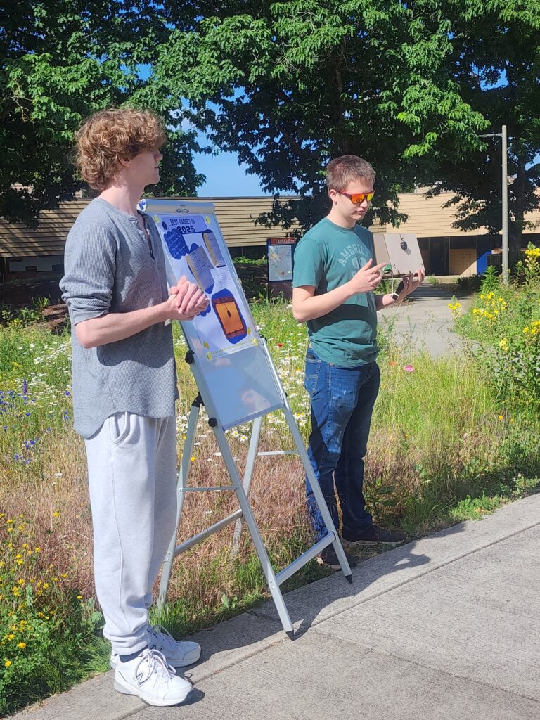 two people stand outside presenting with a small poster.