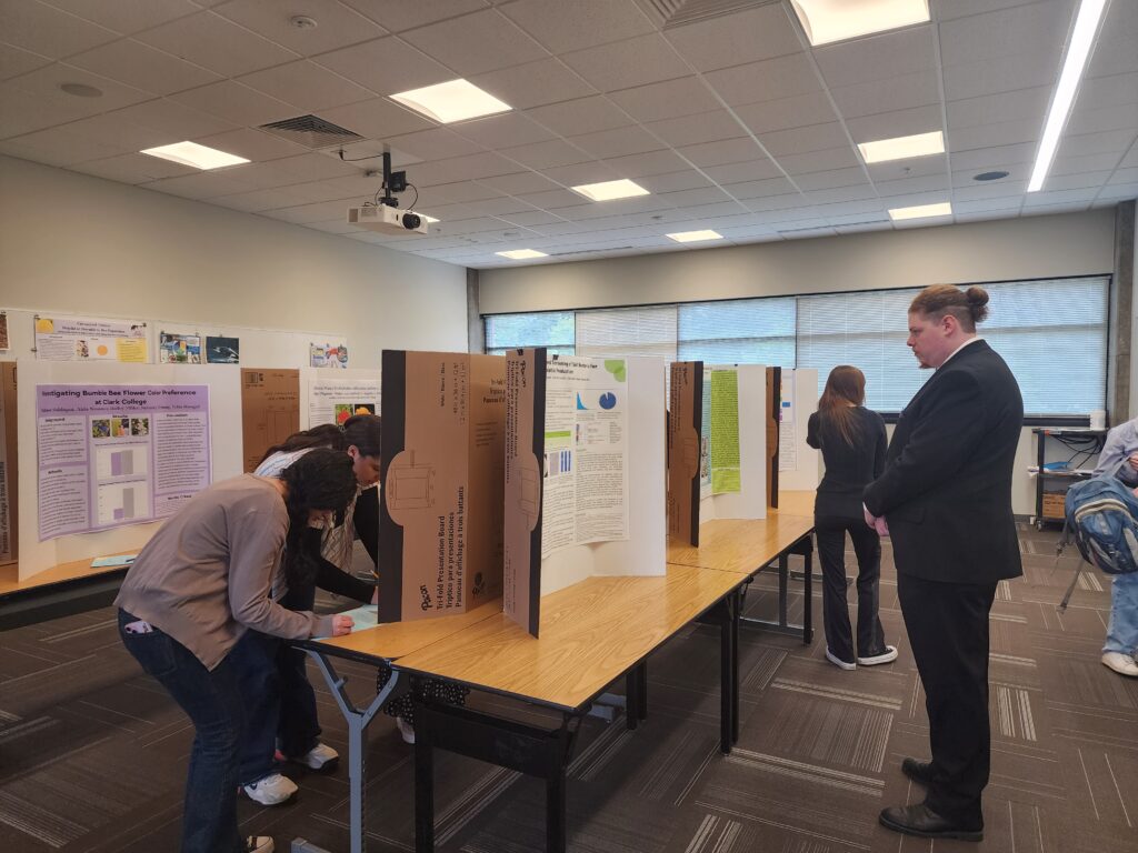 Several people in a room with posters on tables.