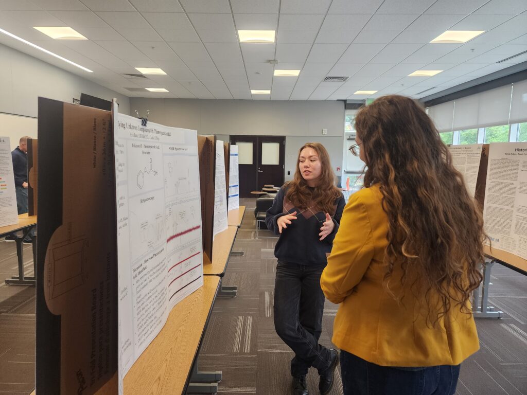 person talking to another person in front of a poster,