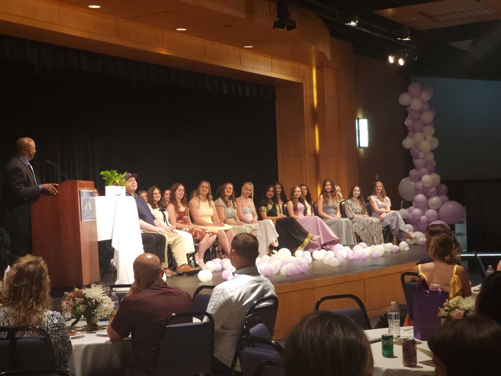Graduates from the recent dental hygiene class seated and listening to a speaker during their ceremony.