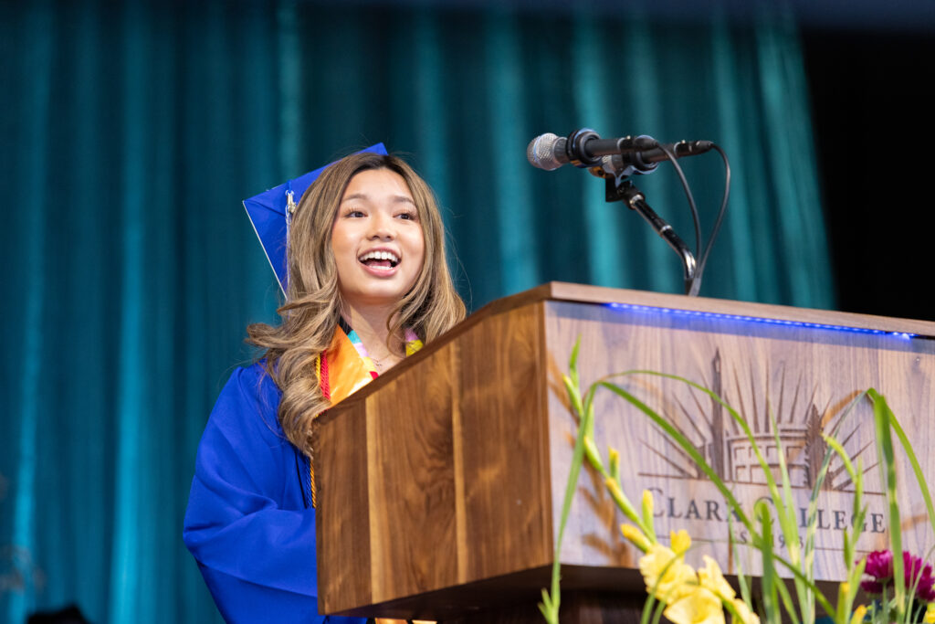 person at podium in cap and gown