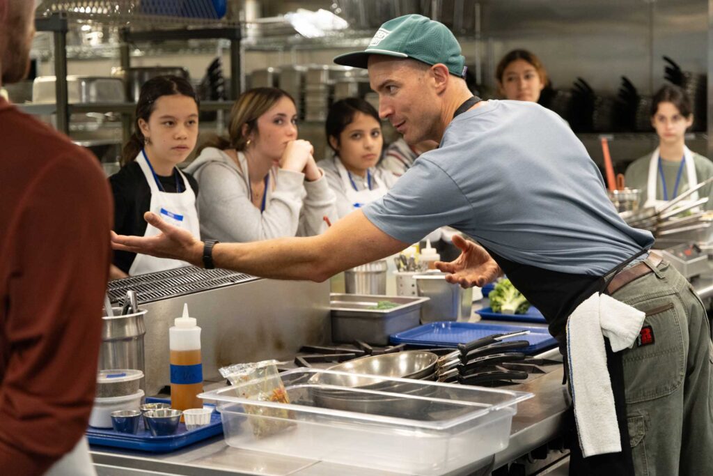 A chef in a kitchen instructing students.