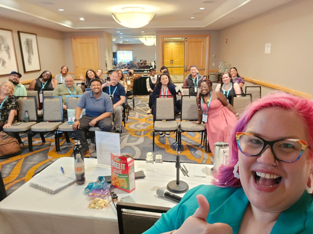 selfie, with people on chairs looking at camera behind them.