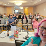 selfie, with people on chairs looking at camera behind them.