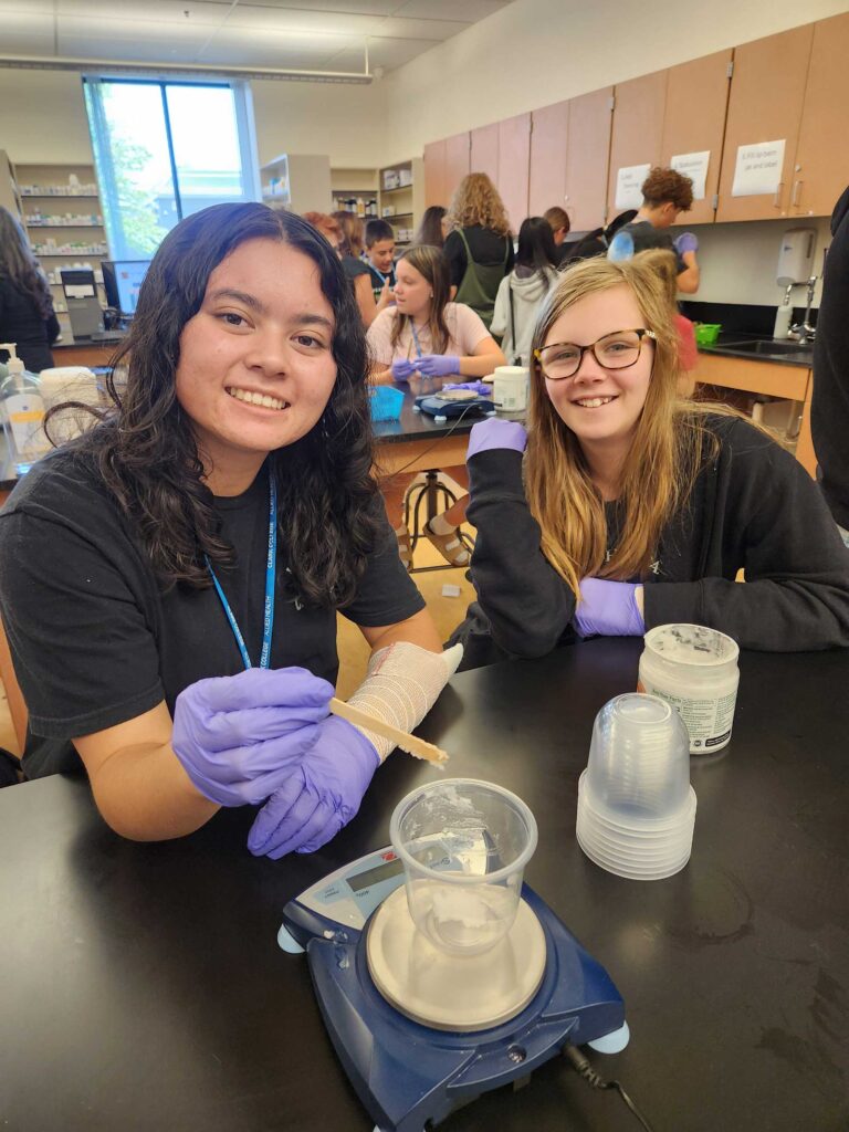 Two kids wearing medical gloves and smiling at the camera.
